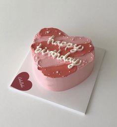 a pink heart shaped cake with happy birthday written on it