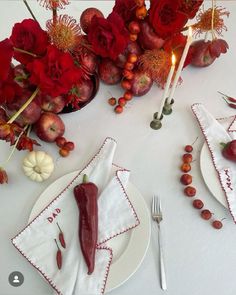 a white table topped with red flowers and fruit