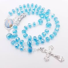 Personalised Crystal Rosary Beads with flat rondelle blue beads. Makes a great gift for First Holy Communion, Baptism, Quinceanera, Christening and more. If you would like to change the centrepiece, please just ask (Communion Chalice, Confirmation Dove, Mary & Baby-Baptism, Miraculous Medal). Use at mass or daily prayer to deepen your prayer life. Give this as a gift or use it as you meditate on the mysteries of the Holy Rosary. These pieces are hand crafted to help promote the Rosary and encour Beaded Rosary For Baptism, Silver Beaded Rosary For First Communion, Blue Spiritual Rosary As A Gift, Pearl Rosary For First Communion, Spiritual Style, Blue Rosary With Round Beads For Gift, Crystal Rosary, Adjustable Cross-shaped Rosary For First Communion, Lady Of Lourdes, Our Lady Of Lourdes