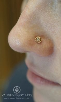 a woman's nose with a gold nose ring on it, and the bottom part of her nose is visible