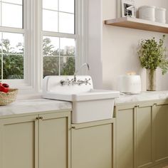 a white kitchen sink sitting under two windows