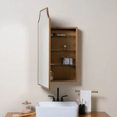 a bathroom sink sitting under a mirror next to a wooden cabinet with shelves above it