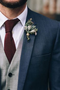 a man wearing a suit and tie with a boutonniere on his lapel