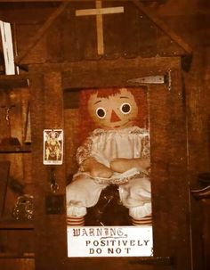 a creepy doll sitting in a wooden frame