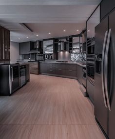 an empty kitchen with stainless steel appliances and wood flooring is pictured in this image