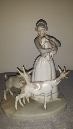 a statue of a woman holding a baby in her arms surrounded by deer and antelope