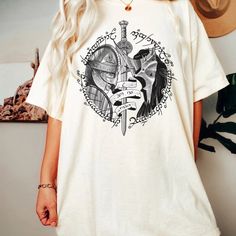 a woman standing in front of a wall wearing a white t - shirt with an image of a knight on it