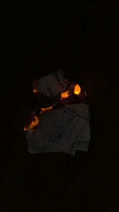 three pieces of paper sitting on top of each other in the dark with lit candles