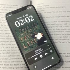 an iphone displaying the time on it's screen sitting on top of a book