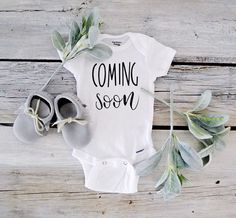 a baby's coming soon shirt with shoes and eucalyptus leaves