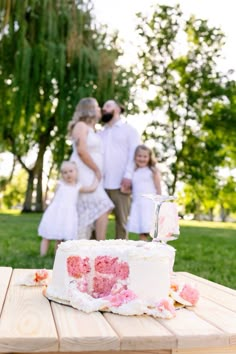 a family standing behind a cake on top of a wooden table