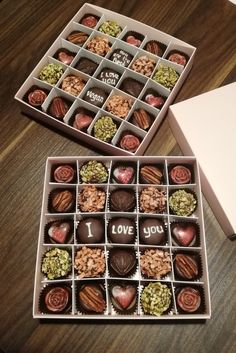 two boxes filled with chocolates on top of a wooden table