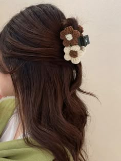 a woman with long brown hair wearing a flower clip in her left hand and holding onto the back of her head