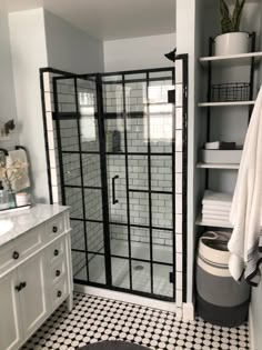 a bathroom with black and white tiles on the floor, shower stall, toilet and sink