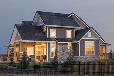 a large house with two story windows and a black fence in front of it at dusk