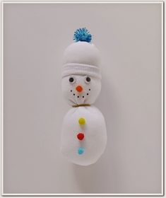 a snowman ornament hanging on a wall with a blue hat and pompom