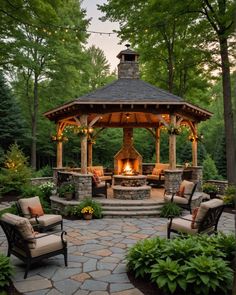 an outdoor gazebo with seating around it and lights on the roof, surrounded by trees