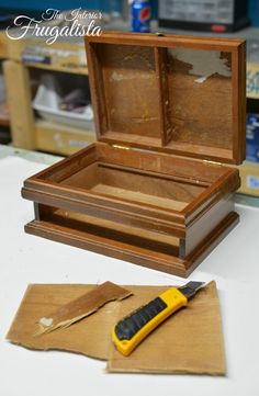 an open wooden box sitting on top of a table next to a pair of scissors