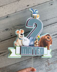 a birthday cake topper with the number two and characters from the movie's secret