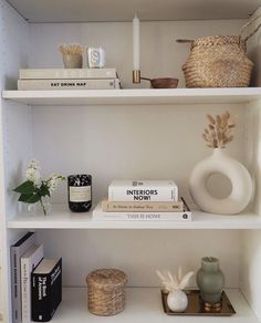 books, vases and other items are on the shelves in this white bookcase