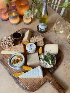 a wooden cutting board topped with cheese and crackers