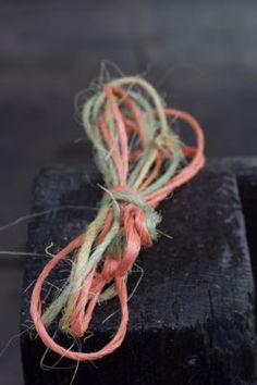 an orange string tied to a black piece of wood