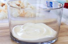 a glass filled with cream sitting on top of a wooden table