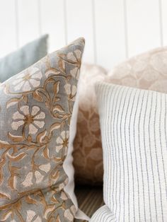 three pillows sitting on top of a bed next to each other in different colors and patterns