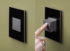 a person pressing the switch button on a green wall with two black and silver switches