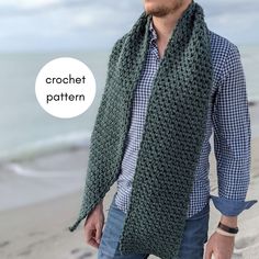 a man standing on the beach wearing a green crochet scarf with a speech bubble above his head