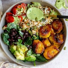 a bowl filled with rice, beans, avocado and other vegetables next to some guacamole