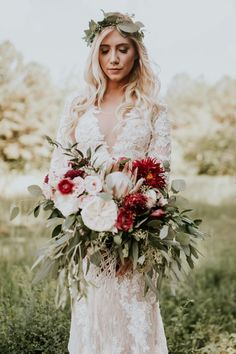 a woman in a wedding dress holding a bouquet of flowers and greenery with her face close to the camera