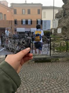 a hand holding up a photo of two people on bicycles in front of some buildings