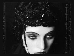 a black and white photo of a woman wearing a head piece with beads on it