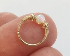 a small gold ring with a white opal stone on it's middle finger