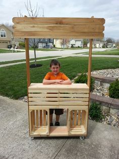 a young boy sitting on top of a wooden structure