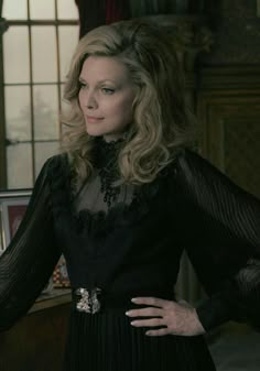 the woman is wearing a black dress with sheer sleeves