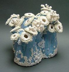 two blue and white vases with flowers on the top one is made out of knitted yarn