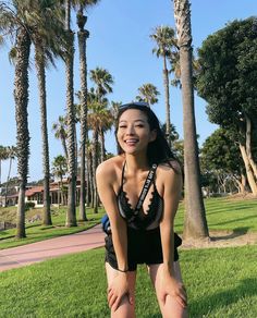 a woman in a bathing suit posing for the camera with palm trees and buildings behind her