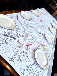 the table is covered with white plates and crayons