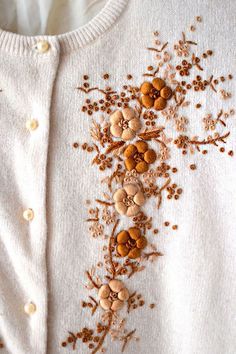 an embroidered sweater with buttons and flowers on it