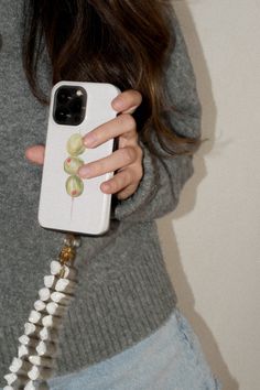 a woman is holding up her phone case with grapes painted on it, while she's looking at the camera