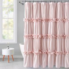 a pink shower curtain with ruffles on it in front of a white bath tub