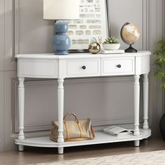 a white table with drawers and a purse on it in front of a wall mounted poster