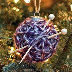 an ornament hanging from a christmas tree decorated with knitting needles and yarn balls