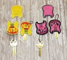 four key chains with different designs on them sitting next to each other in front of a wooden surface