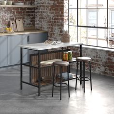 a kitchen with an island and stools next to a brick wall in the background