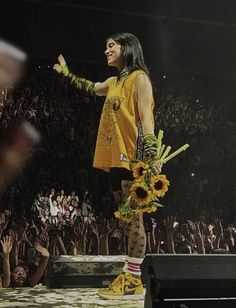 a woman standing on top of a stage with sunflowers in front of her