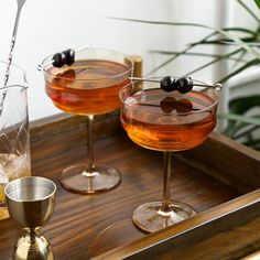 two glasses filled with drinks sitting on top of a wooden tray