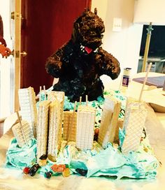 there is a cake made to look like a godzilla with skyscrapers on it and buildings in the background